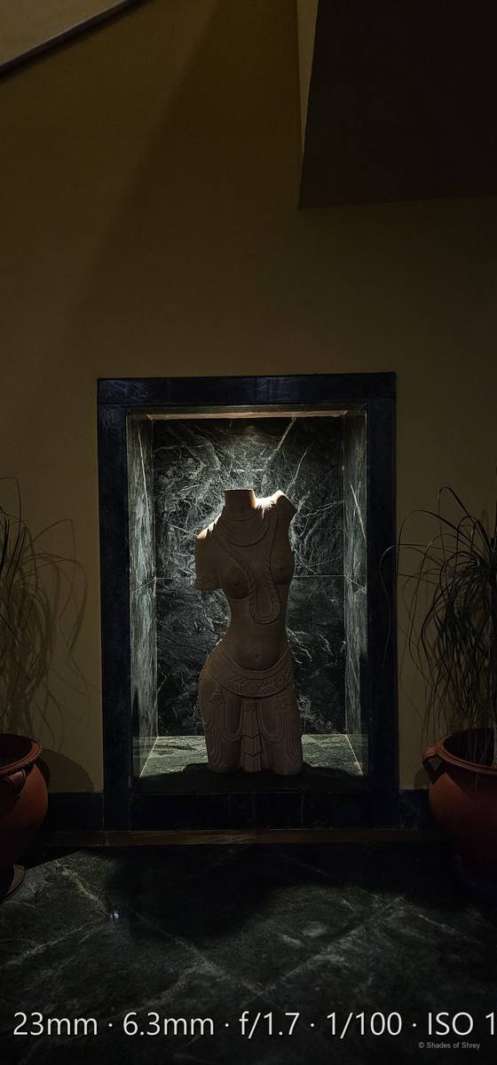 Carved wooden figure illuminated by warm light on a green marble pedestal
