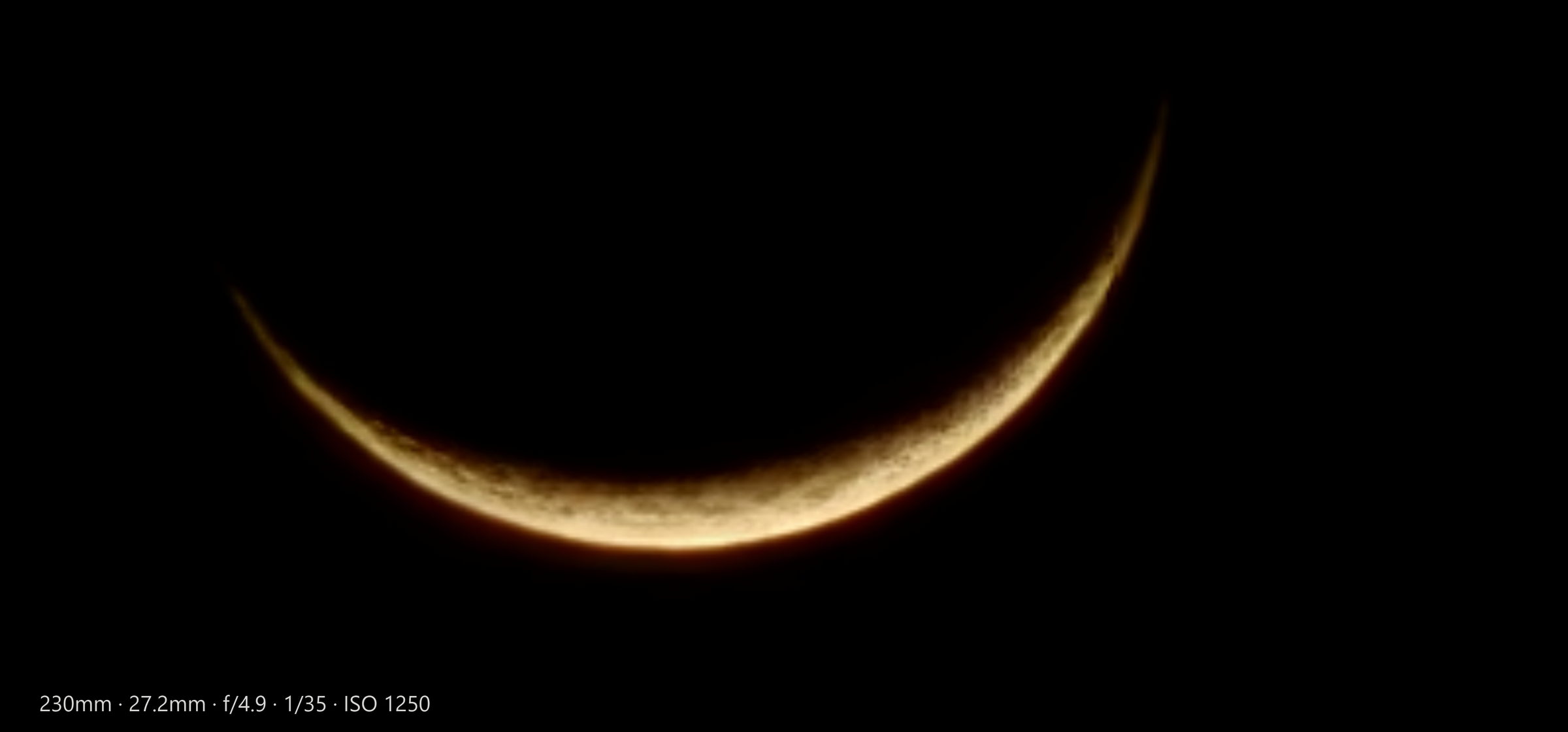 Golden crescent moon against deep black sky