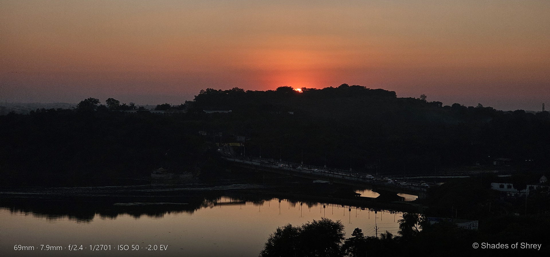 Sunset behind hillside with bridge and river reflections