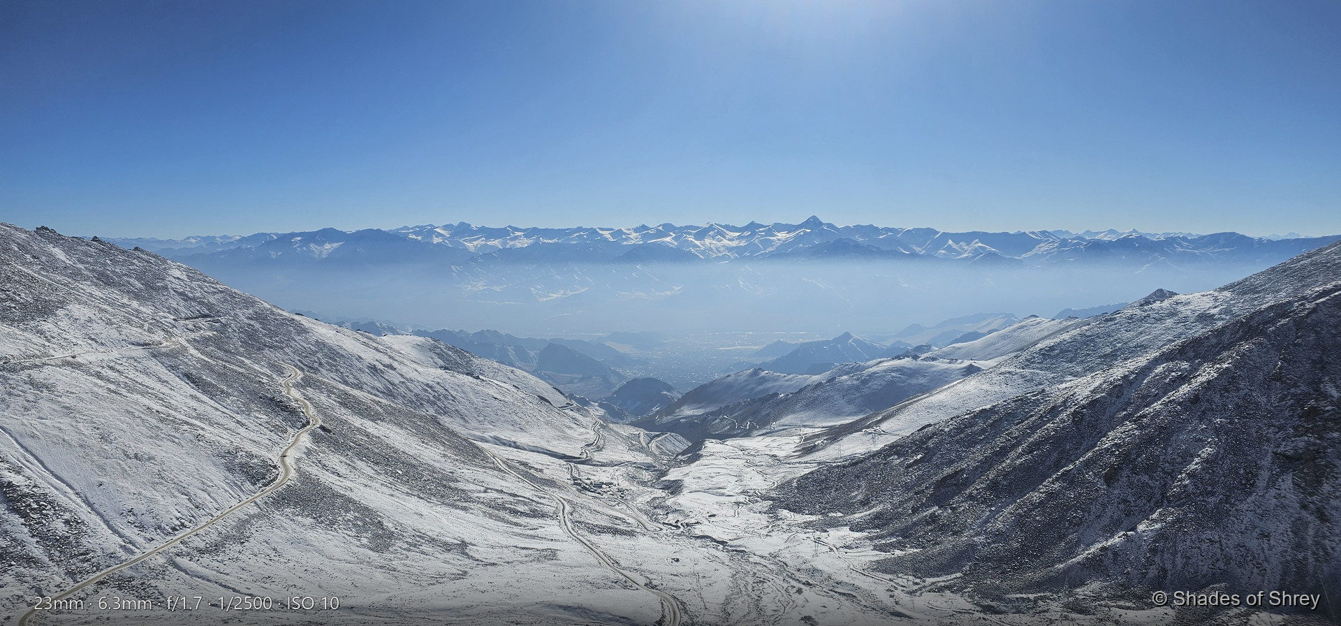 Sweeping snow-covered mountain pass under clear blue sky