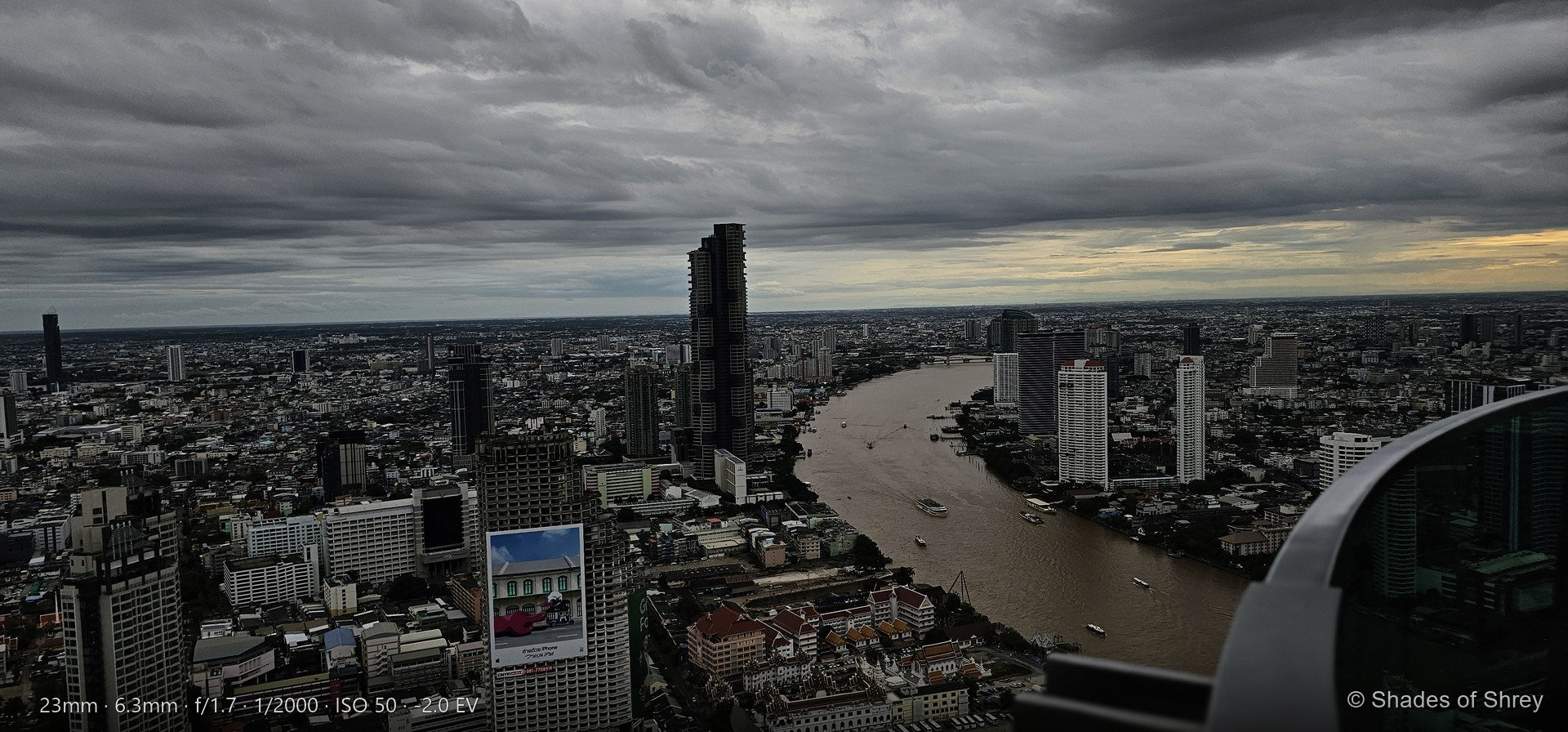 Aerial view of Bangkok skyline with Chao Phraya River winding through the city under dramatic monsoon clouds