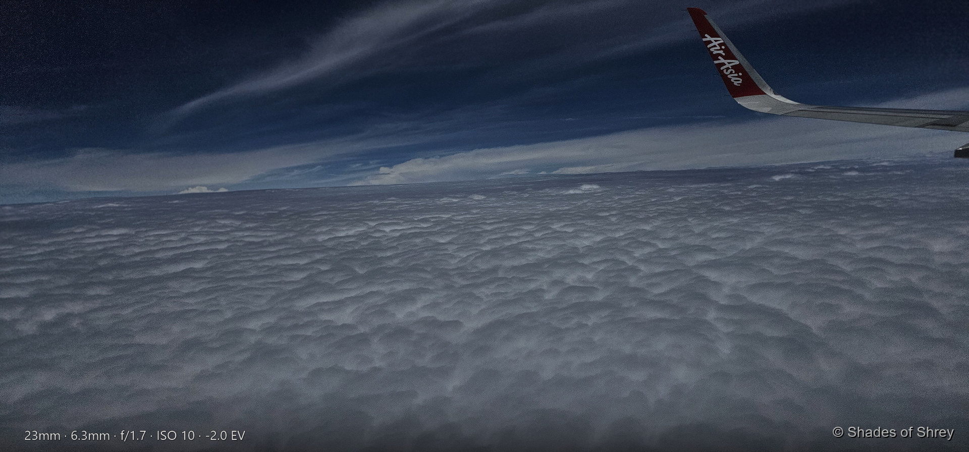 Endless cloudscape seen from an AirAsia flight window, rippled white clouds stretching to the horizon