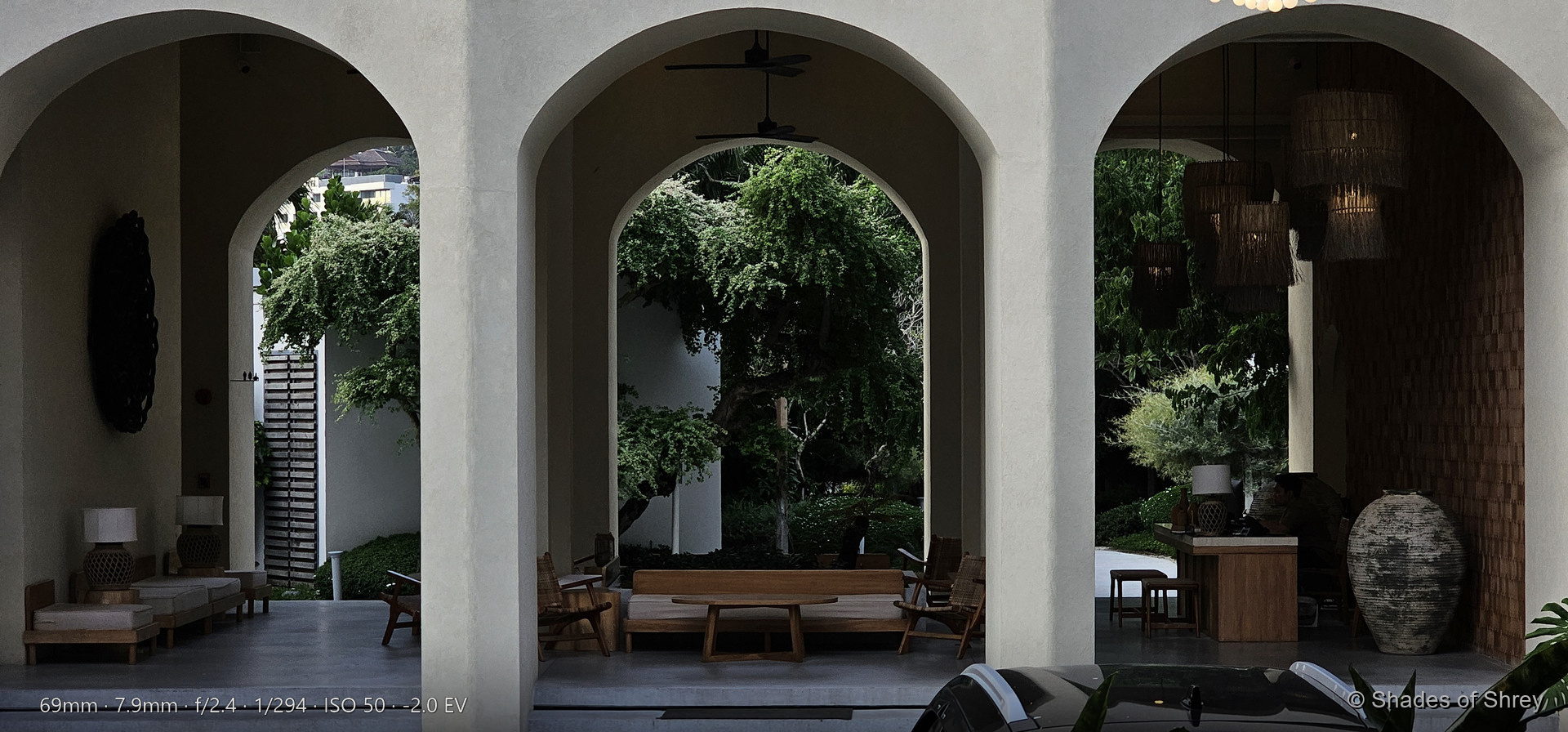 Modern resort courtyard with curved arched openings framing lush tropical gardens