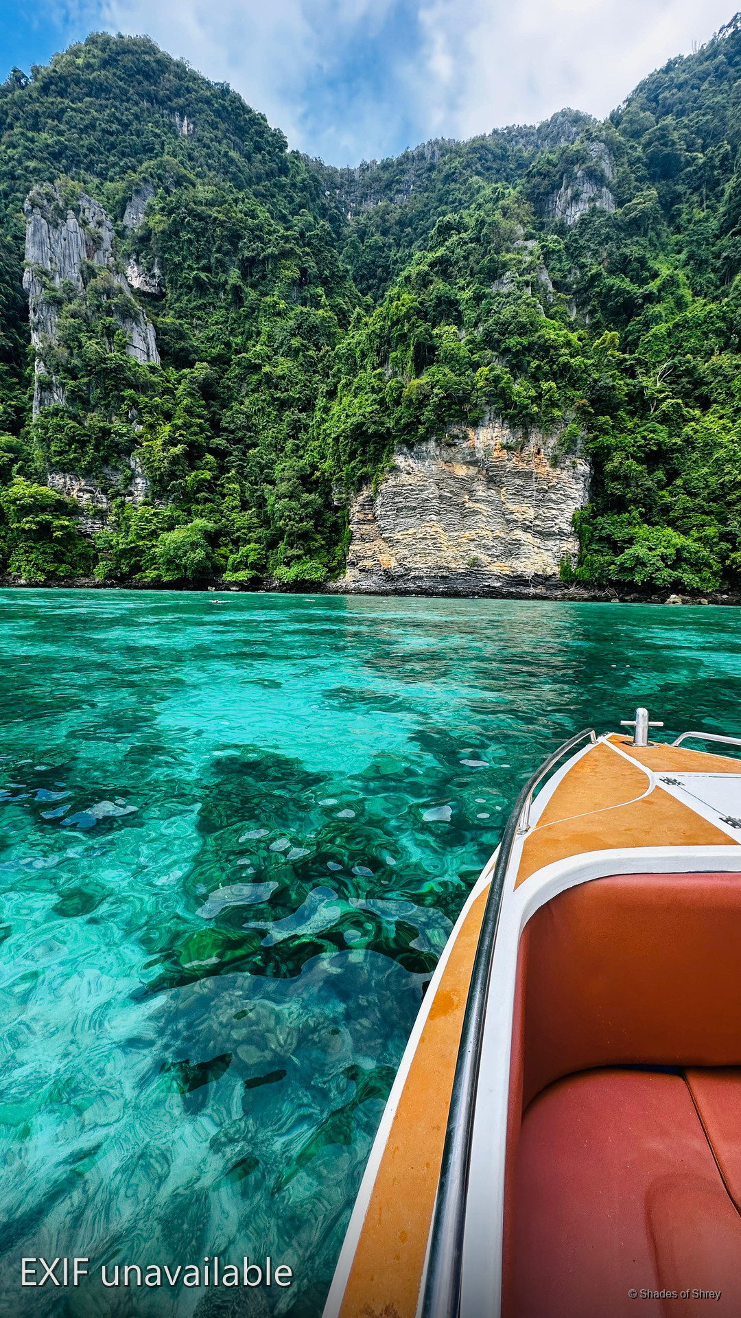 Crystal clear turquoise waters of Phi Phi Islands from a speedboat, limestone cliffs rising behind